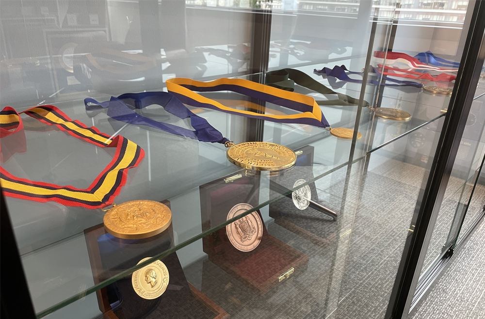 A row of medals and awards in a glass container.